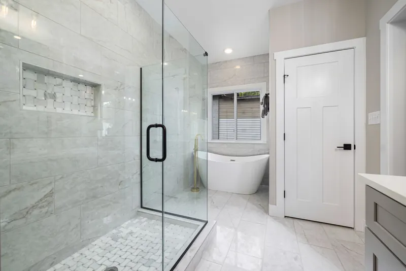 Frameless glass shower door with a black handle