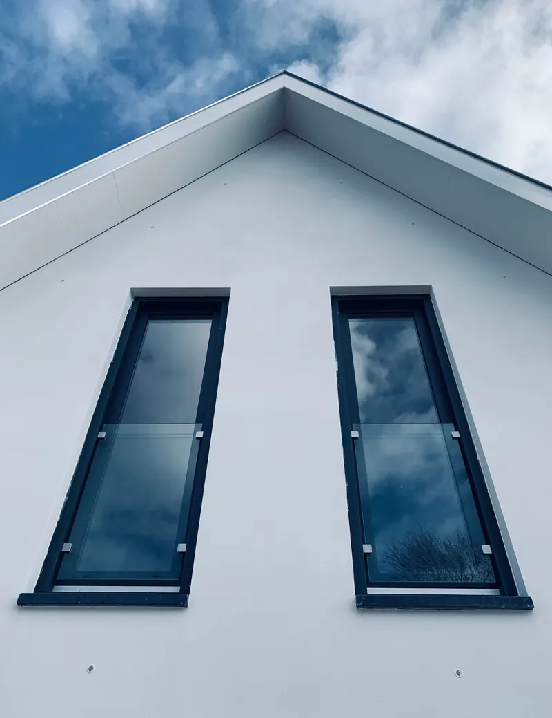 Two tall windows on the white gable of a house